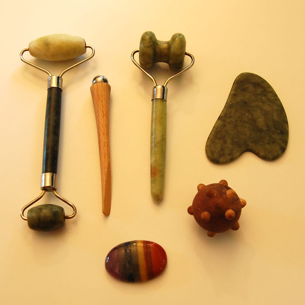A set of facial Reflexology and massage tools – jade rollers, a gua sha, a stone and a spiky ball