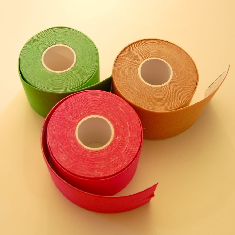 Rolls of kinesiology tape in green, beige and red